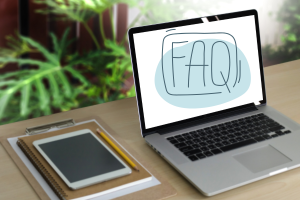 Laptop on a desk showing 'FAQ' on the screen, surrounded by office supplies, symbolizing an informative guide to frequently asked questions about performance bonds in Florence, Alabama.