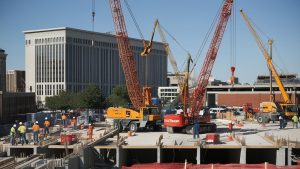 Dynamic construction project in Little Rock, AR, showing workers, heavy machinery, and collaborative efforts on a sunny day.