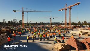 Construction site in Baldwin Park, California, featuring cranes, workers, and an expansive concrete structure under development.