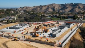 Aerial view of a construction project in Chino Hills, California, featuring foundation work, heavy equipment, and picturesque rolling hills in the background.