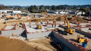 Construction site in Folsom, California, featuring cranes and heavy machinery in action. Workers are seen actively managing the project, showcasing a dynamic building process.