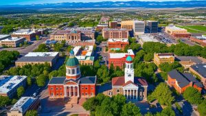 Aerial view of downtown Fort Collins, Colorado, showcasing the blend of historic and modern architecture with green spaces and the Rocky Mountains in the distance.