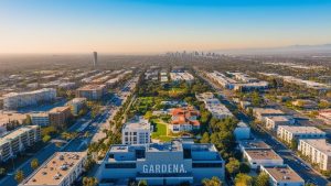 A stunning aerial view of Gardena, California, highlighting urban architecture, green spaces, and a glimpse of Los Angeles in the distance.