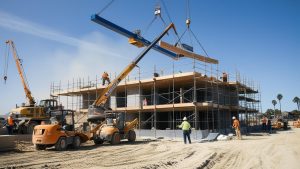 Construction site in Laguna Niguel, California featuring cranes, construction vehicles, and workers actively building a structure, showcasing local development and infrastructure projects.