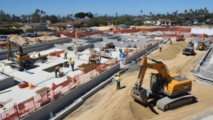 Aerial view of a construction foundation in Laguna Niguel, California, with excavators, workers, and machinery, highlighting a detailed phase of a large-scale building project.