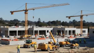 Active construction project in Lake Forest, CA, with multiple cranes and heavy equipment on-site, illustrating the robust construction industry in the area and potential needs for performance bonds.