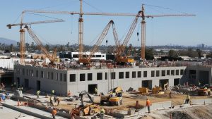 Construction site in Montebello, California, showcasing active cranes and workers on a multi-level building project, emphasizing the importance of performance and construction payment bonds for project security.