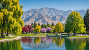 an image showcasing a serene lakeside park in Moreno Valley, CA. Include families picnicking, children playing, and ducks swimming in the lake. Show colorful trees, a walking trail, and distant mountains.