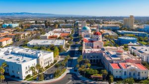 Aerial view of Tustin, California, showcasing the city’s architecture, iconic buildings, and surrounding landscape under a clear blue sky.