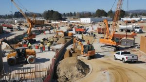 Construction site in Woodland, California, showcasing heavy machinery and workers actively engaged in a large-scale infrastructure project under clear skies.