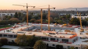 Construction site with cranes and workers at sunset in Buena Park, California, highlighting development and growth in the city.