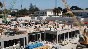 Construction site in Culver City, California, featuring workers in safety gear on a concrete framework surrounded by cranes and construction equipment.