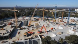 Large construction site in Hemet, California, with cranes and machinery actively working on a building project under clear skies.