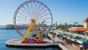 The iconic Ferris wheel at Balboa Fun Zone in Newport Beach, California, surrounded by shops and colorful umbrellas. Infrastructure and entertainment projects like this benefit from performance bonds.