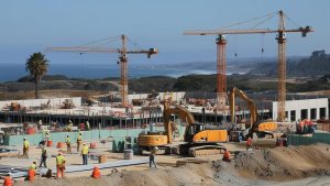 Construction site in Rancho Palos Verdes, California, featuring cranes and workers with a scenic ocean view in the background.