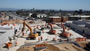 Aerial view of a large construction project in Yuba City, California, with multiple excavators and workers illustrating the role of performance bonds in ensuring project completion.