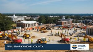 A construction site in Augusta-Richmond County, Georgia, featuring workers, heavy machinery, and historical-style buildings in the background, showcasing local infrastructure development.