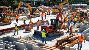 A bustling construction site in Fort Myers, Florida, showcasing workers, heavy equipment, and building materials in a vibrant development project setting.