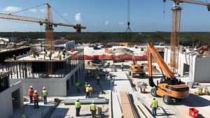 Active construction site in Jupiter, Florida, featuring cranes, workers, and ongoing building projects under a clear blue sky.