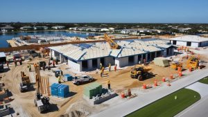 Construction site in Miramar, Florida showcasing workers and heavy machinery actively building new infrastructure by a serene waterfront setting.