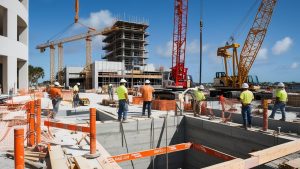 Construction site in Panama City, Florida, showcasing workers, cranes, and ongoing urban development under a bright blue sky.