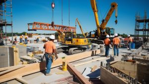 Construction workers at a busy building site in Peoria, Illinois, operating cranes and heavy machinery for a large-scale project.