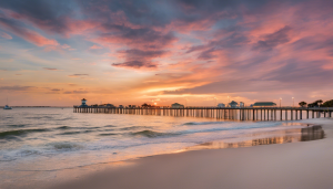 Breathtaking sunset over a pier at the beach in Port Orange, Florida, showcasing tranquil ocean waves, vivid sky colors, and a serene coastal atmosphere.