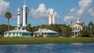 Scenic view of the Kennedy Space Center rockets alongside historic houses in Titusville, Florida, surrounded by lush greenery and calm water.