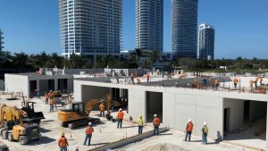 Construction workers on-site in Doral, Florida, with high-rise buildings in the background, showcasing ongoing development and urban growth.