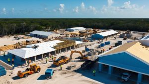 Aerial view of a construction site in North Port, Florida, featuring active machinery and workers building modern structures amidst a natural forest backdrop.