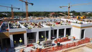 Active construction site in Sarasota, Florida, showcasing workers and cranes building a modern structure.