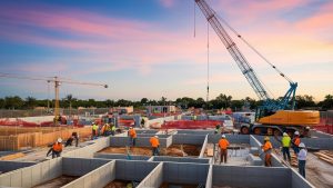 Sunset view of a construction site in Sarasota, Florida, with workers and cranes assembling a foundation.