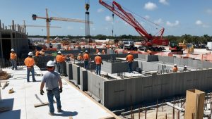 Active construction project in Orlando, Florida, featuring workers in safety gear, cranes, and heavy machinery in a developing urban area.