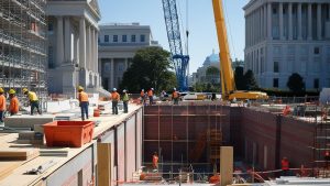 Construction workers and heavy machinery on a large infrastructure project near iconic government buildings in Washington, DC, showcasing progress and activity in public works.