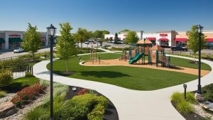 Playground surrounded by lush greenery and shopping centers in Orland Park, Illinois, showcasing the town's family-friendly and commercial environment.