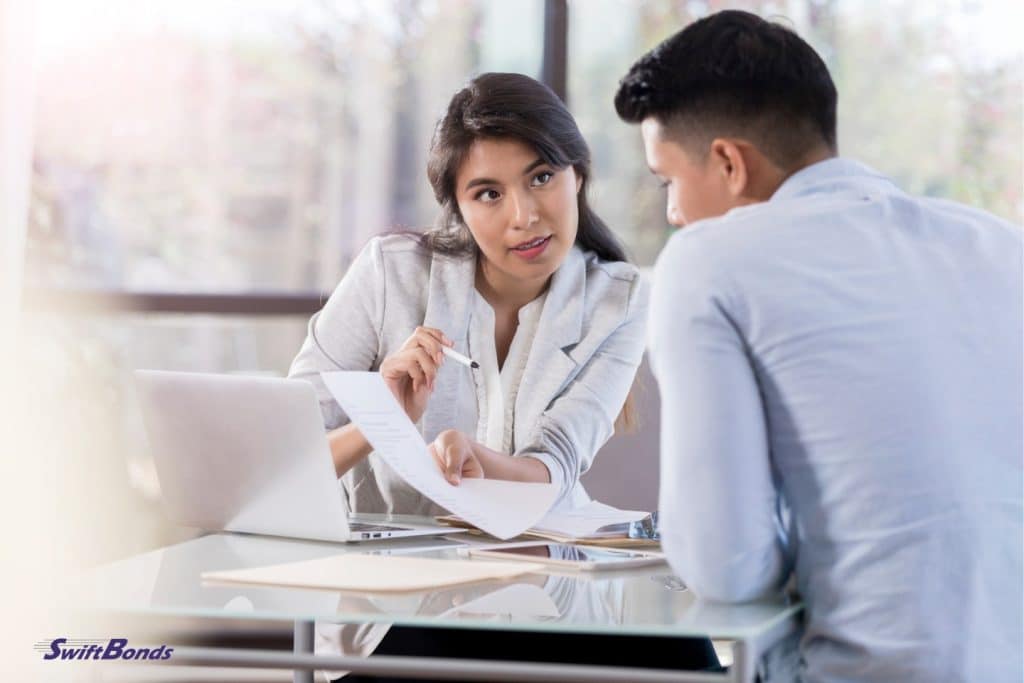 A serious woman talks to a male employee about a document.
