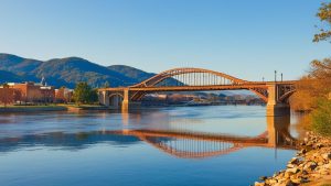 Walnut Street Bridge spanning the Tennessee River in Chattanooga, TN with scenic mountain backdrop and clear blue sky