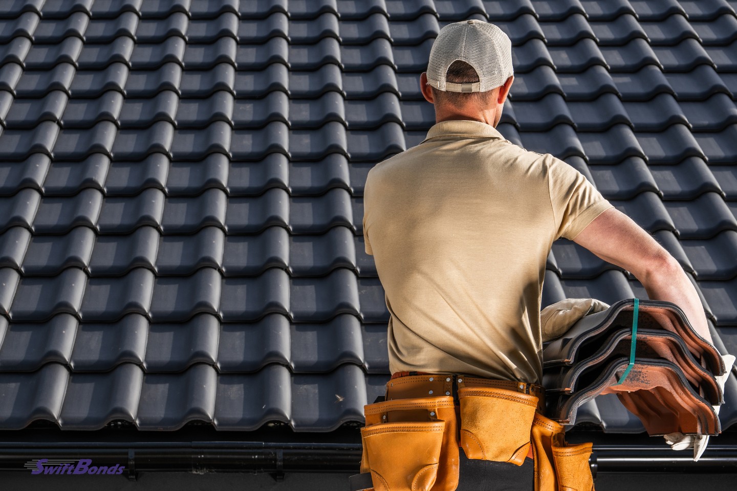 A professional roofer is shown handling ceramic tiles for a black roof.
