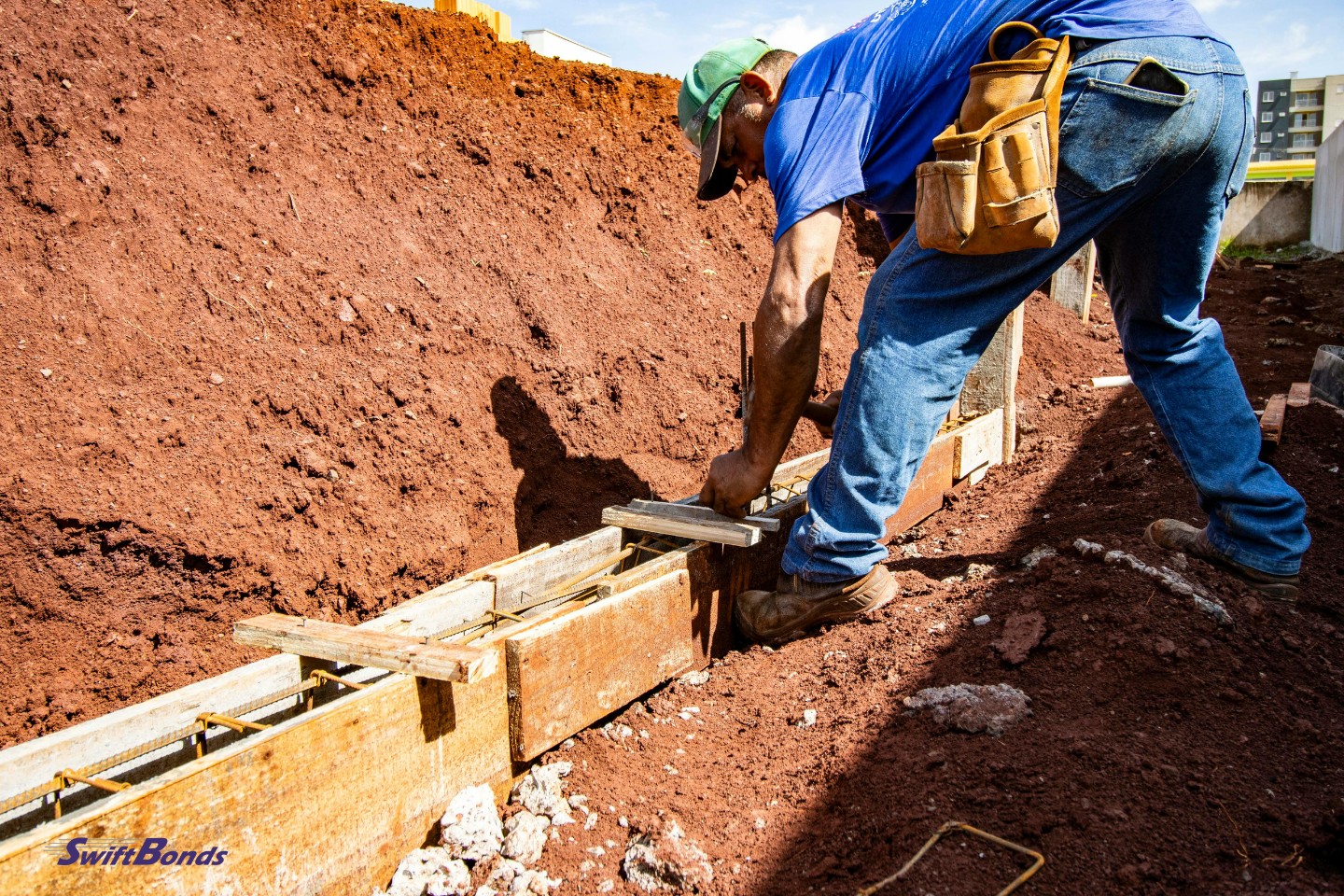 Outside, a construction worker is laying a foundation.