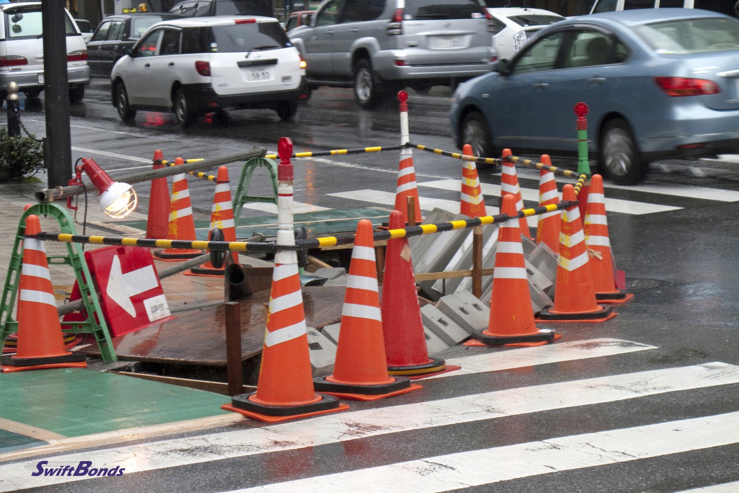 A sidewalk next to curb construction.  The sewer is being built.  There are safety barriers everywhere.