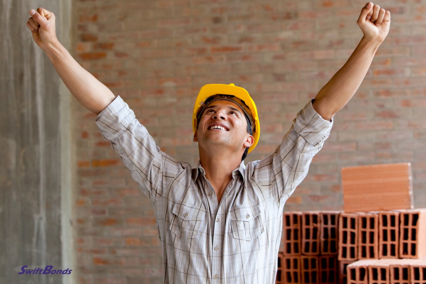 Arms up, a contented construction worker at a building site.
