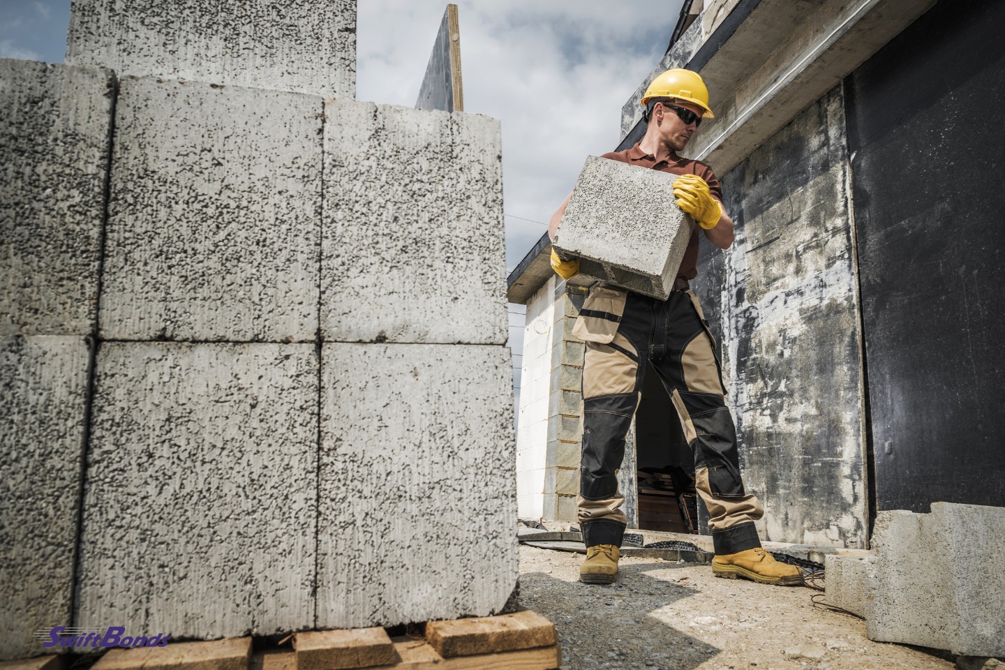 A construction worker is carrying building materials. Delivery of hollow dense concrete blocks.