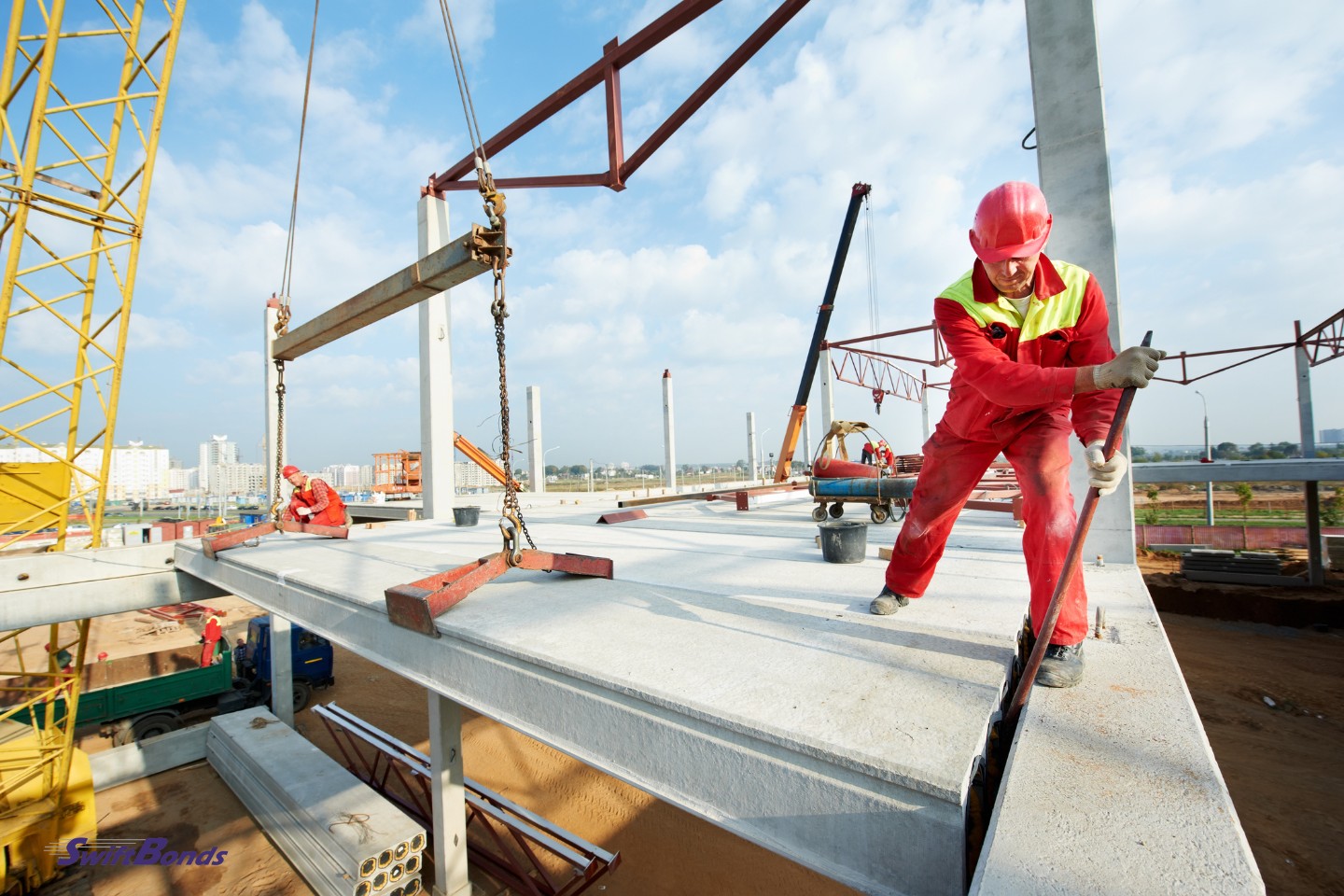 During building construction, a worker wearing safety gear installs concrete floor slab panels.