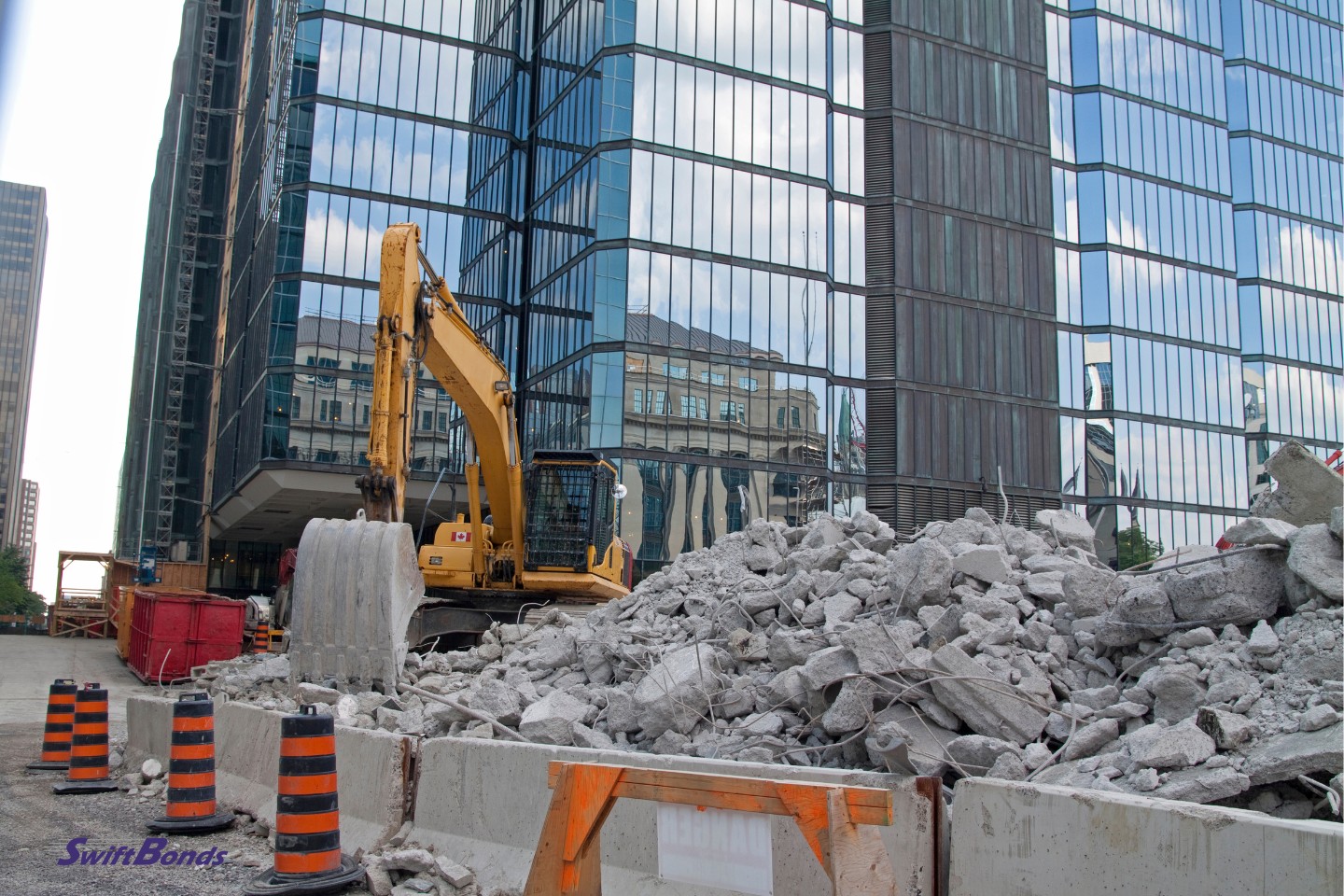 An excavator and a mound of shattered concrete in the middle of the city, with a modern building in the background.