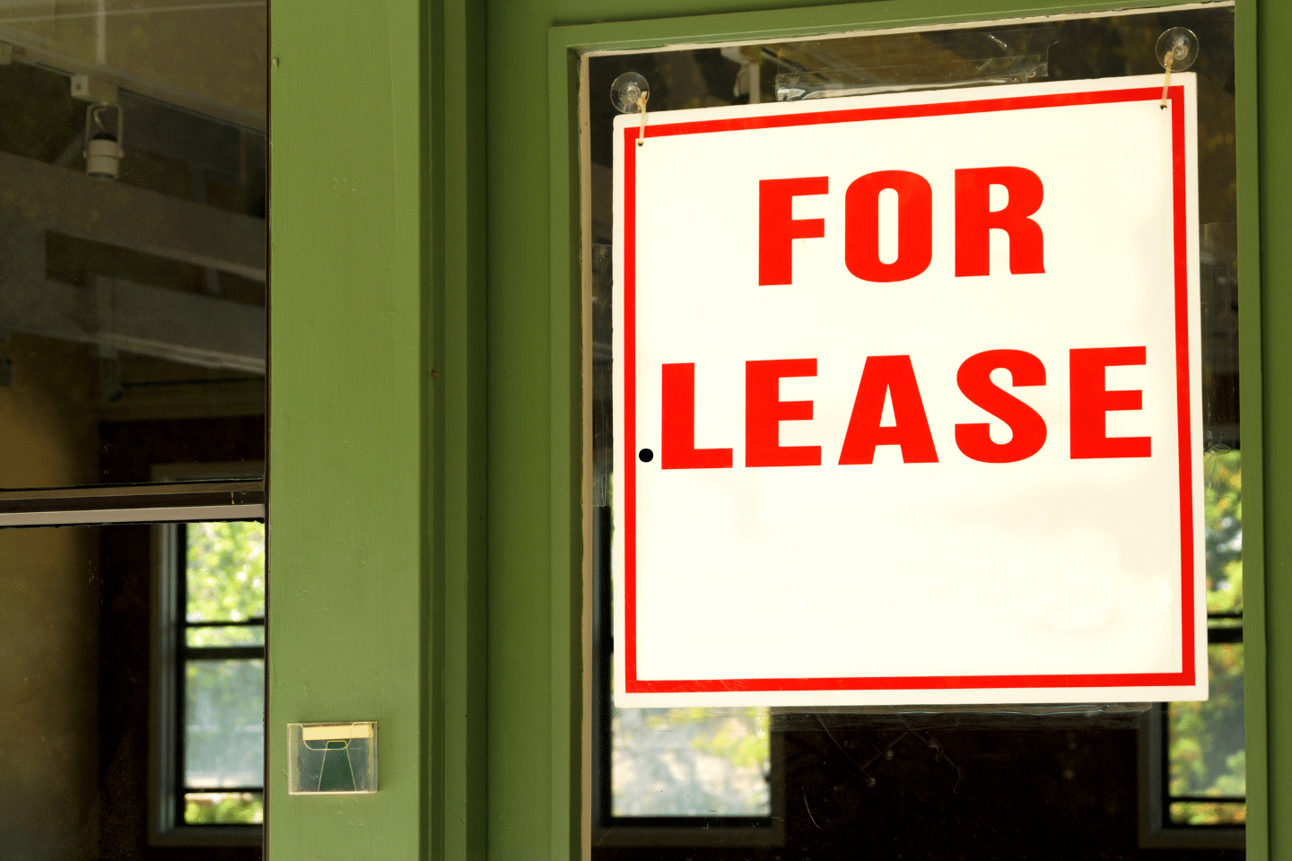A bright red “For Lease” sign displayed on the window of a commercial property.