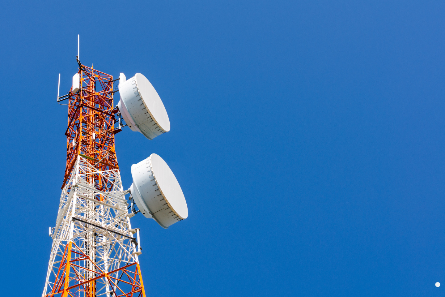 Red and white communication tower equipped with large satellite dishes.