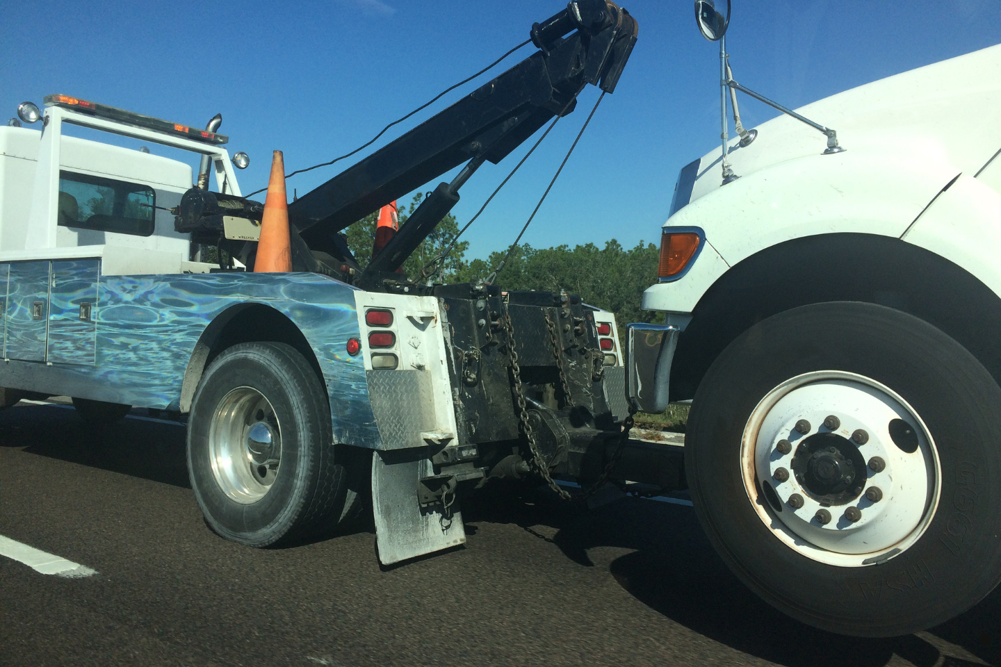 Heavy-duty tow truck pulling a large commercial truck on the road.