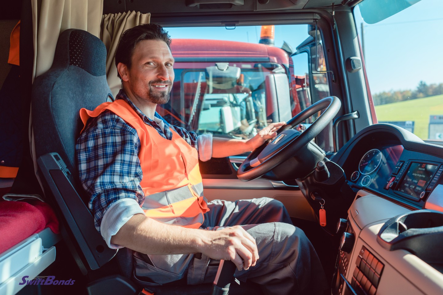 The driver of a truck or lorry sits in the cabin of his car.