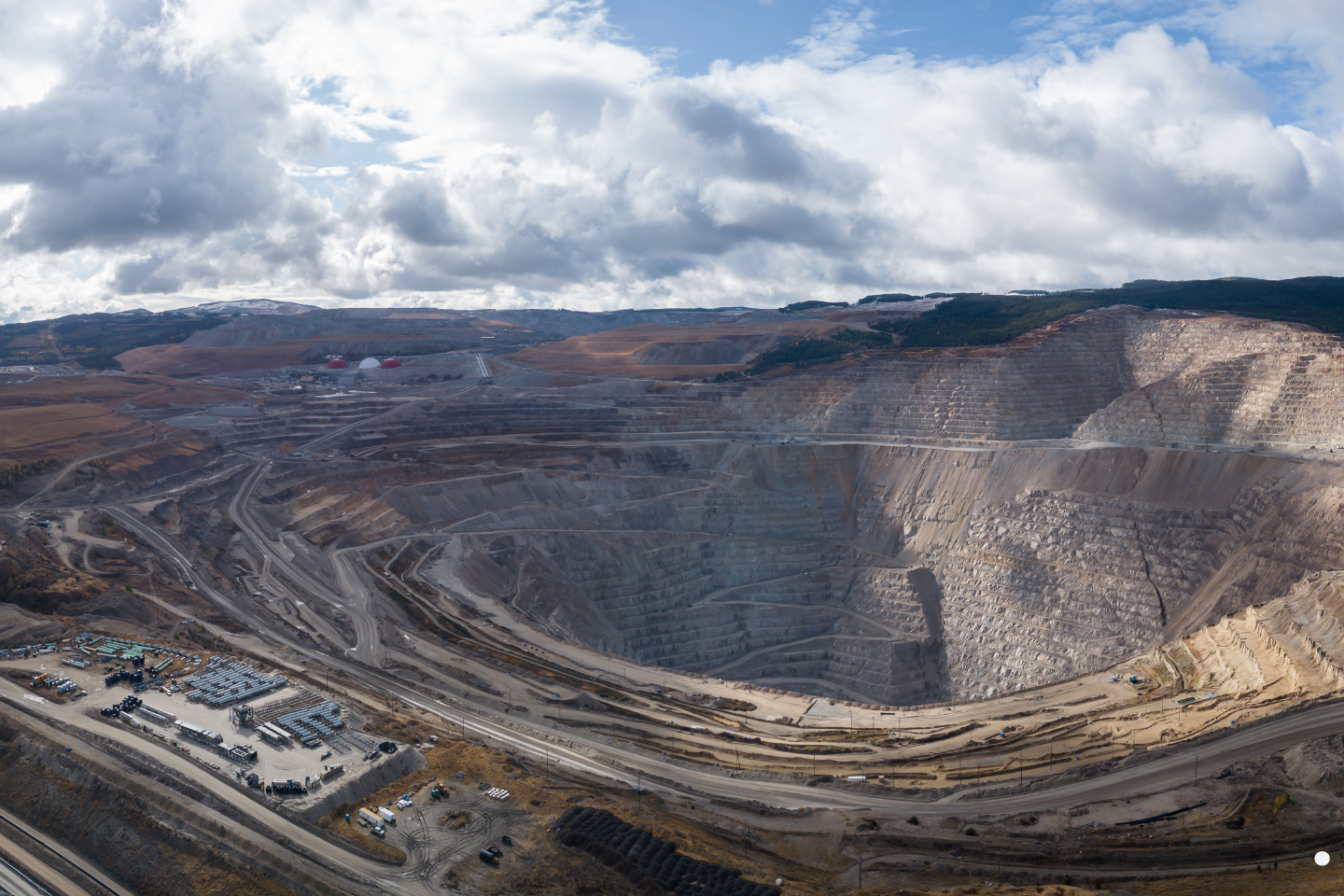 A wide aerial view of an expansive open-pit mining operation with terraced excavation levels.
