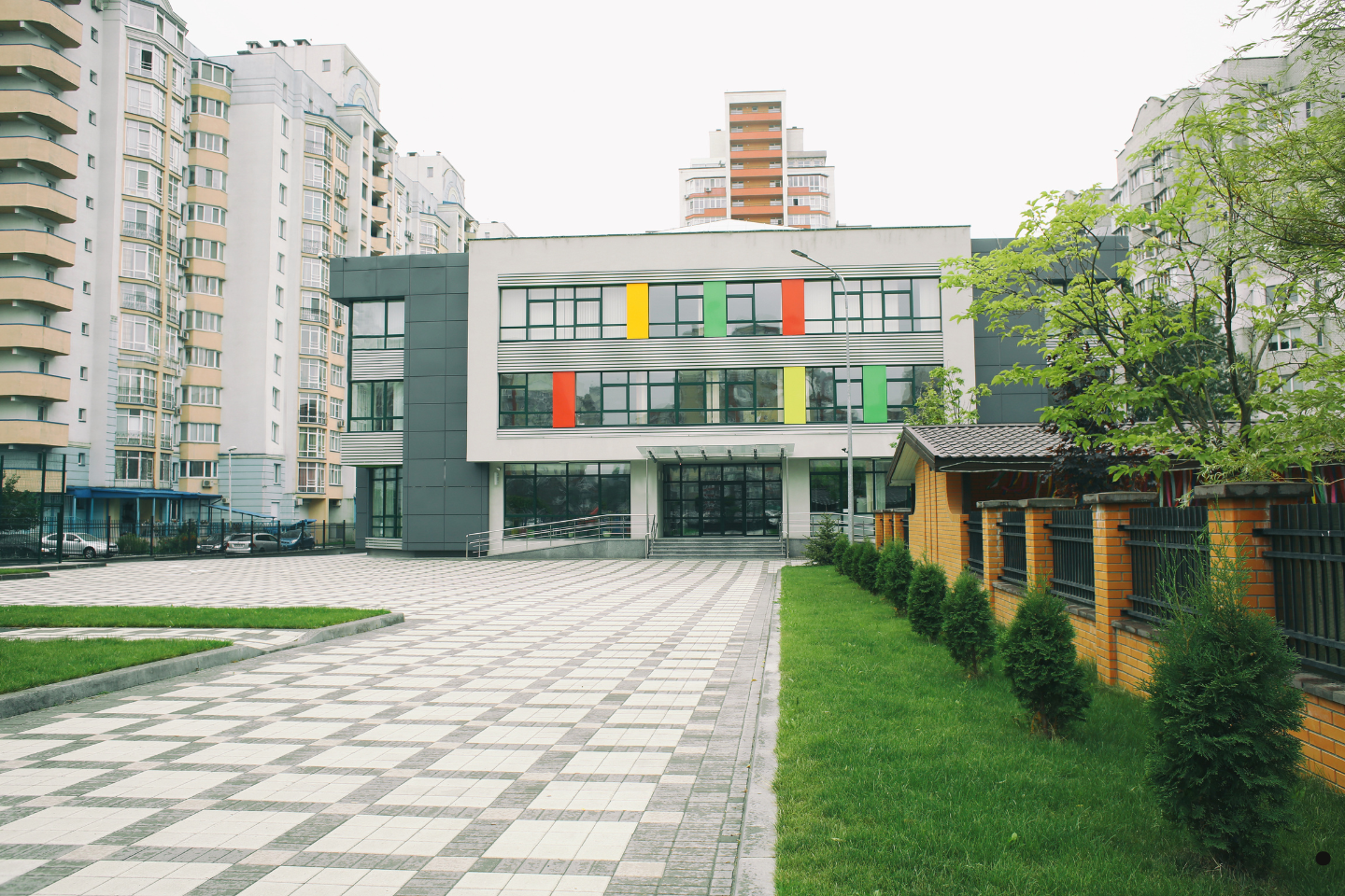 A modern school building with colorful window panels surrounded by high-rise apartments.